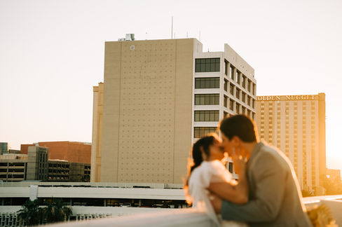 Bride and groom pose for pictures in downtown las vegas at golden hour with the strip in the background. captured by las vegas wedding photographer brazen honey films. Groom wears stylish stottish kilt. Bride wears custom made with love bridal gown.