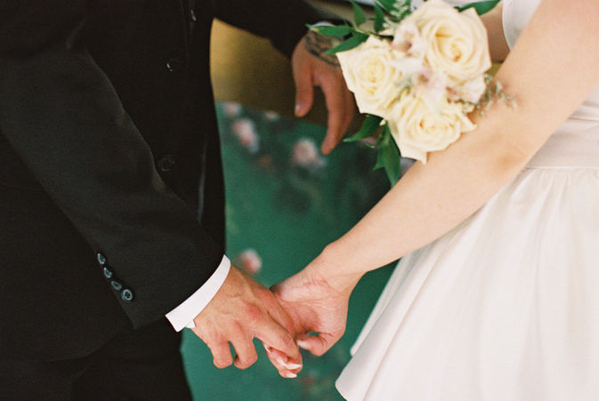 bride and groom wearing wedding attire hold hands in the tunnel of love at the little white wedding chapel with cupid mural overhead