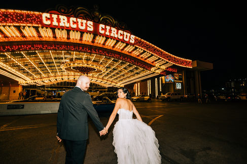 Bride and groom pose under the neon lights in downtown las vegas riding in the back of a convertible blue thunderbird. Captured by las vegas elopement photographer brazen honey films