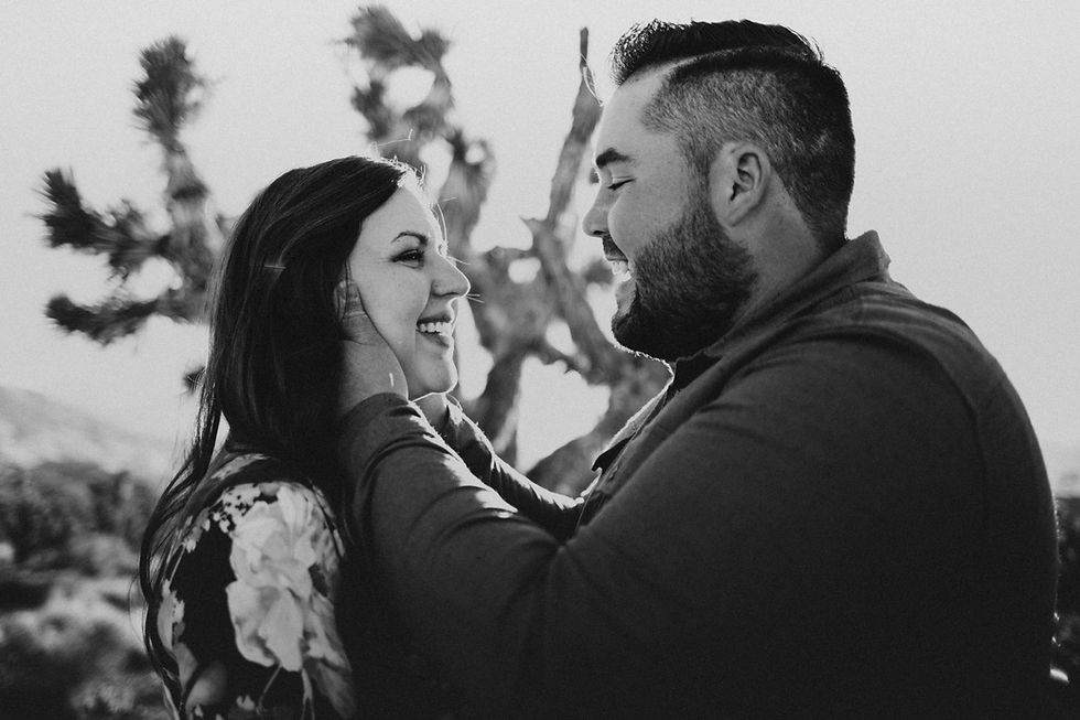 Black and white capture of joyful engagement photos where man holds his wifes face and they laugh captured by las vegas family photographer