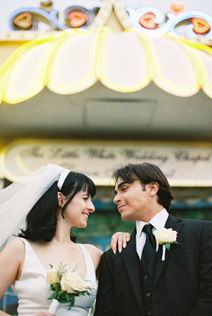 bride and groom wearing wedding attire take photos outside of the little white wedding chapel in las vegas