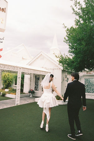 bride and groom wearing wedding attire take photos outside of the little white wedding chapel in las vegas
