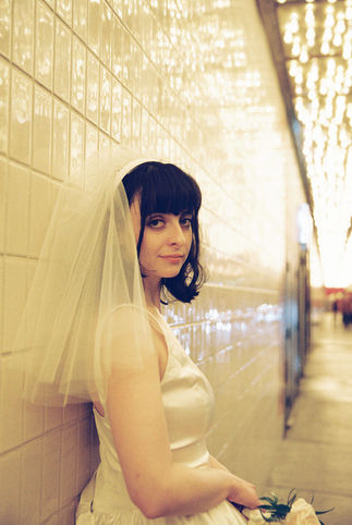 bride wearing white with a veil poses underneath golden neon lights in las vegas