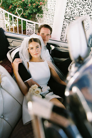 bride and groom snuggle together in the front seat of a convertible
