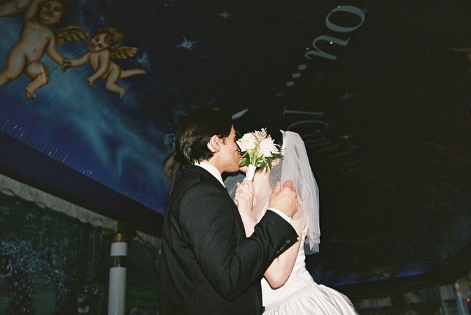 bride and groom wearing wedding attire hold hands in the tunnel of love at the little white wedding chapel with cupid mural overhead