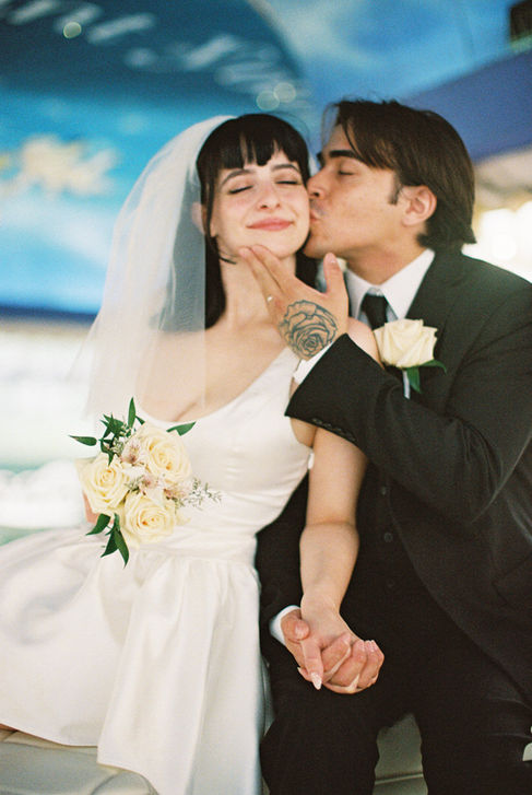 bride and groom wearing wedding attire take photos outside of the little white wedding chapel in las vegas