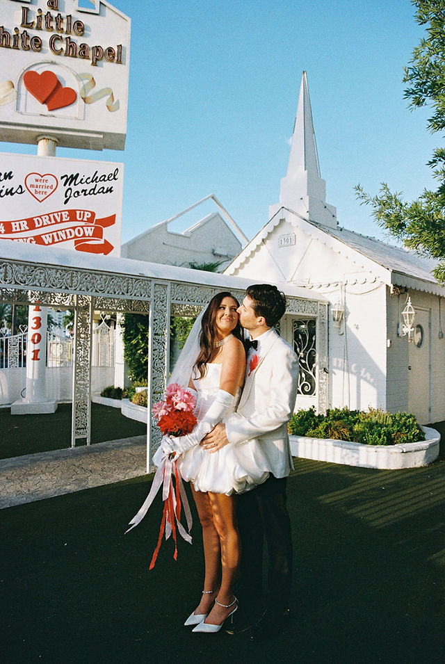 Las Vegas film photographer brazen honey films captures couple from New Zealand who got married at the little white wedding chapel. Bride wears short white gown with red and pink florals from Lucid Juliet. 35mm film photos.