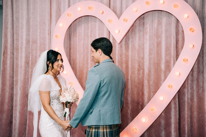 Bride and groom stand holding hands at the heart altar of the sure thing chapel. Groom stands at the altar at the sure thing chapel waiting for his bride. Captured by las vegas elopement photographer brazen honey films