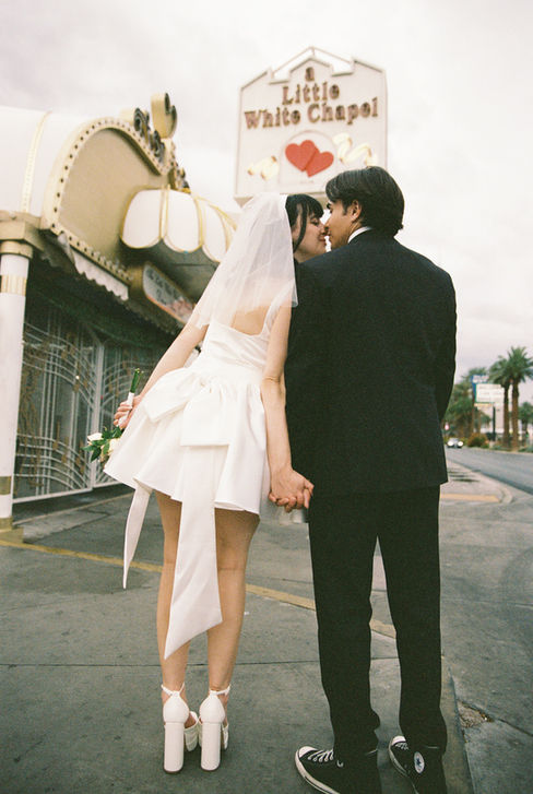 bride and groom wearing wedding attire take photos outside of the little white wedding chapel in las vegas