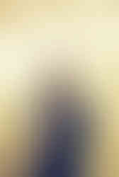 groom wearing black tuxedo poses underneath the golden neon lights at the plaza hotel