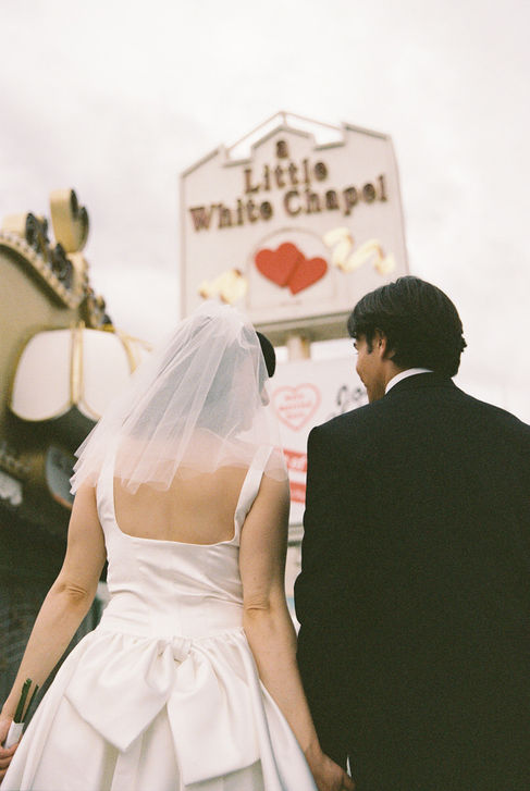 bride and groom wearing wedding attire take photos outside of the little white wedding chapel in las vegas