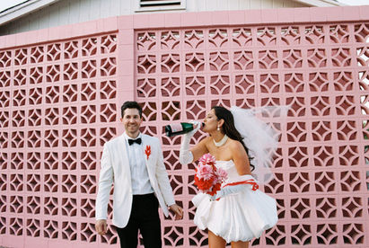 Las Vegas film photographer brazen honey films captures couple from New Zealand who got married at the little white wedding chapel. Bride wears short white gown with red and pink florals from Lucid Juliet. 35mm film photos taken under colorful murals and neon lights.