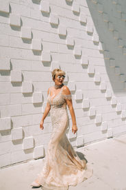 Bride walks down the sidewalk of downtown vegas wearing champagne colored rhinestones stress and sunglasses. Captured by las vegas elopement photographer brazen honey films
