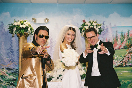 bride and groom pose with elvis impersanator at the little white chapel and point towards the camera