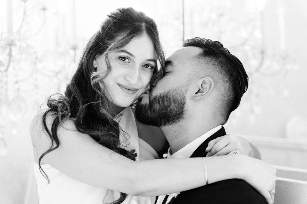 Black and white photograph of bride and groom kissing. Bride and groom kiss under the neon las Vegas sign. Rent a vintage wedding car. Bride and groom drive the Las Vegas Strip at night in classic convertible mustang. Best places to take wedding day pictures in Las Vegas. captured by las Vegas elopement photographer brazen honey films