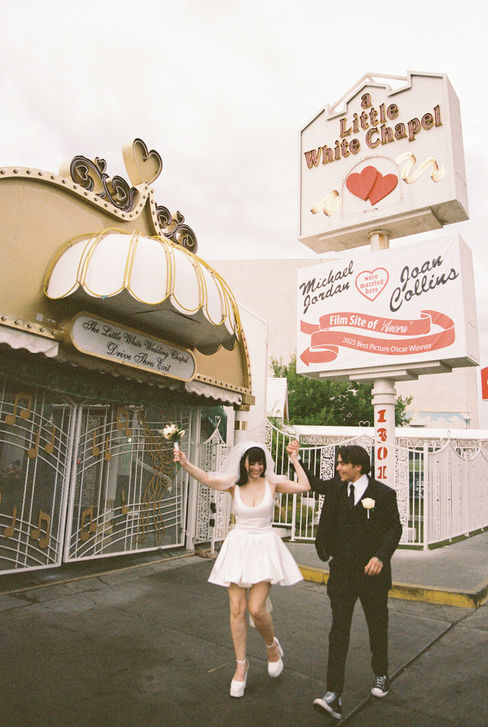 bride and groom wearing wedding attire take photos outside of the little white wedding chapel in las vegas 