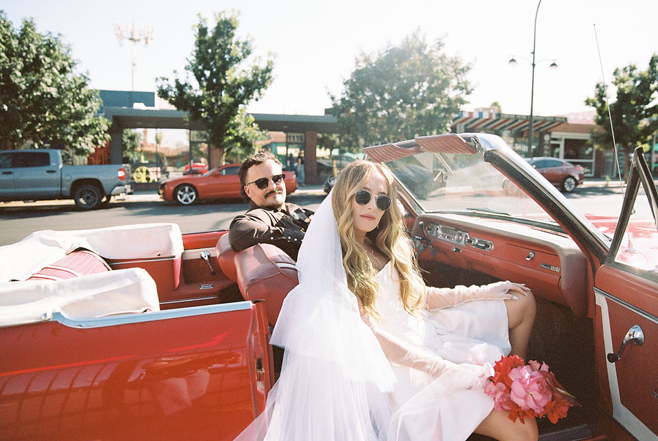 35mm film photo by las vegas elopement photographer brazen honey films. couple takes pictures with cherry red vintage convertible