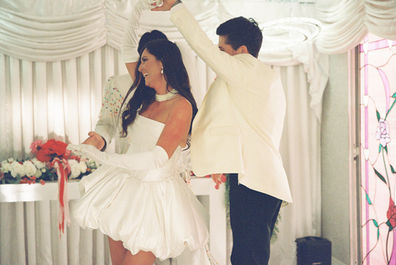 Las Vegas film photographer brazen honey films captures couple from New Zealand who got married at the little white wedding chapel. Bride wears short white gown with red and pink florals from Lucid Juliet. 35mm film photos.