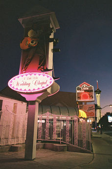 little white wedding chapel neon lights of elvis captured at night, pink and red glowing signs