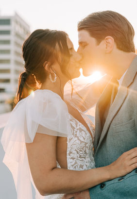 Bride and groom pose for pictures in downtown las vegas at golden hour with the strip in the background. captured by las vegas wedding photographer brazen honey films. Groom wears stylish stottish kilt. Bride wears custom made with love bridal gown.