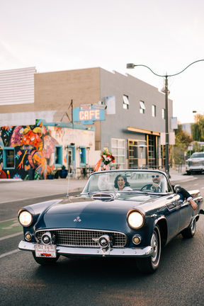 Bride and groom drive down fremont street on their wedding day in a blue convertible thunderbird classic car. captured by las vegas elopement photographer brazen honey films