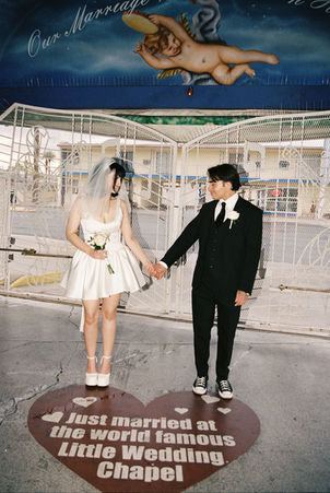bride and groom wearing wedding attire hold hands in the tunnel of love at the little white wedding chapel with cupid mural overhead