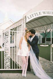 A couple in formal attire kiss outside the little white wedding chapel in las vegas nevada