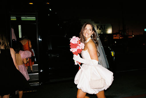 Las Vegas film photographer brazen honey films captures couple from New Zealand who got married at the little white wedding chapel. Bride wears short white gown with red and pink florals from Lucid Juliet. 35mm film photos taken under colorful murals and neon lights.