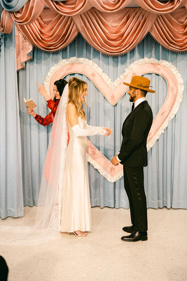 california couple gets married at sure thing chapel in las vegas, captured by film wedding photographer brazen honey films. Blue vintage cutrains and pink heart altar give this kitschy wedding chapel all the vintage vibes.