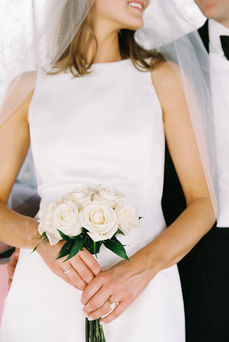 bride holds white bouquet flowers and has short brown hair