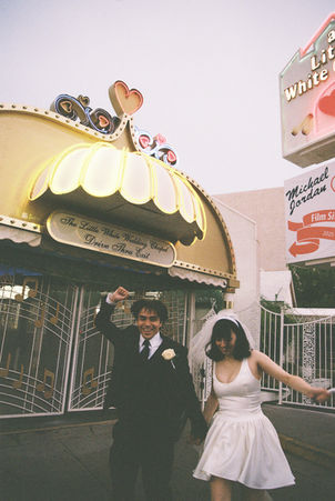 bride and groom wearing wedding attire take photos outside of the little white wedding chapel in las vegas