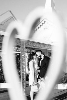 Bride and groom kiss in front of the little white wedding chapel. Black and white photograph Captured by las Vegas elopement photographer brazen honey films.
