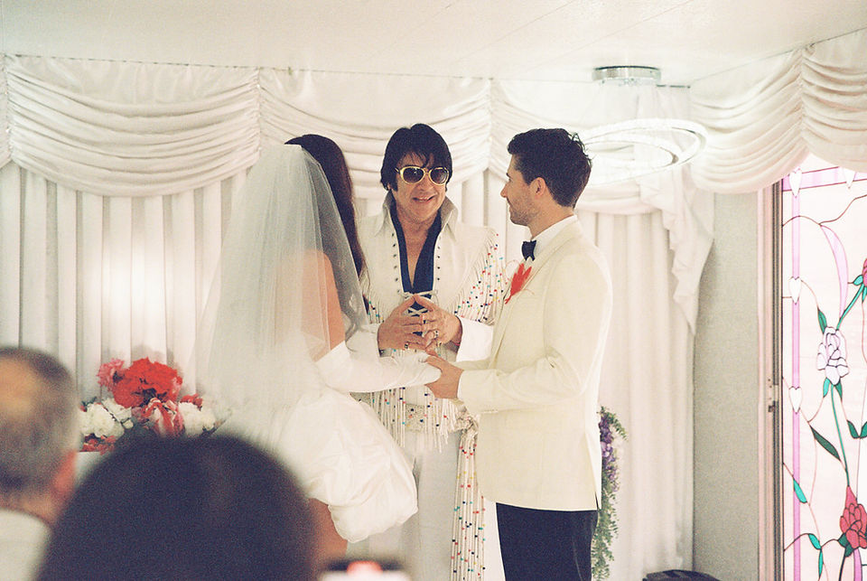 Las Vegas film photographer brazen honey films captures couple from New Zealand who got married at the little white wedding chapel. Bride wears short white gown with red and pink florals from Lucid Juliet. 35mm film photos.
