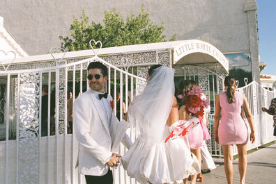 Las Vegas film photographer brazen honey films captures couple from New Zealand who got married at the little white wedding chapel. Bride wears short white gown with red and pink florals from Lucid Juliet. 35mm film photos.