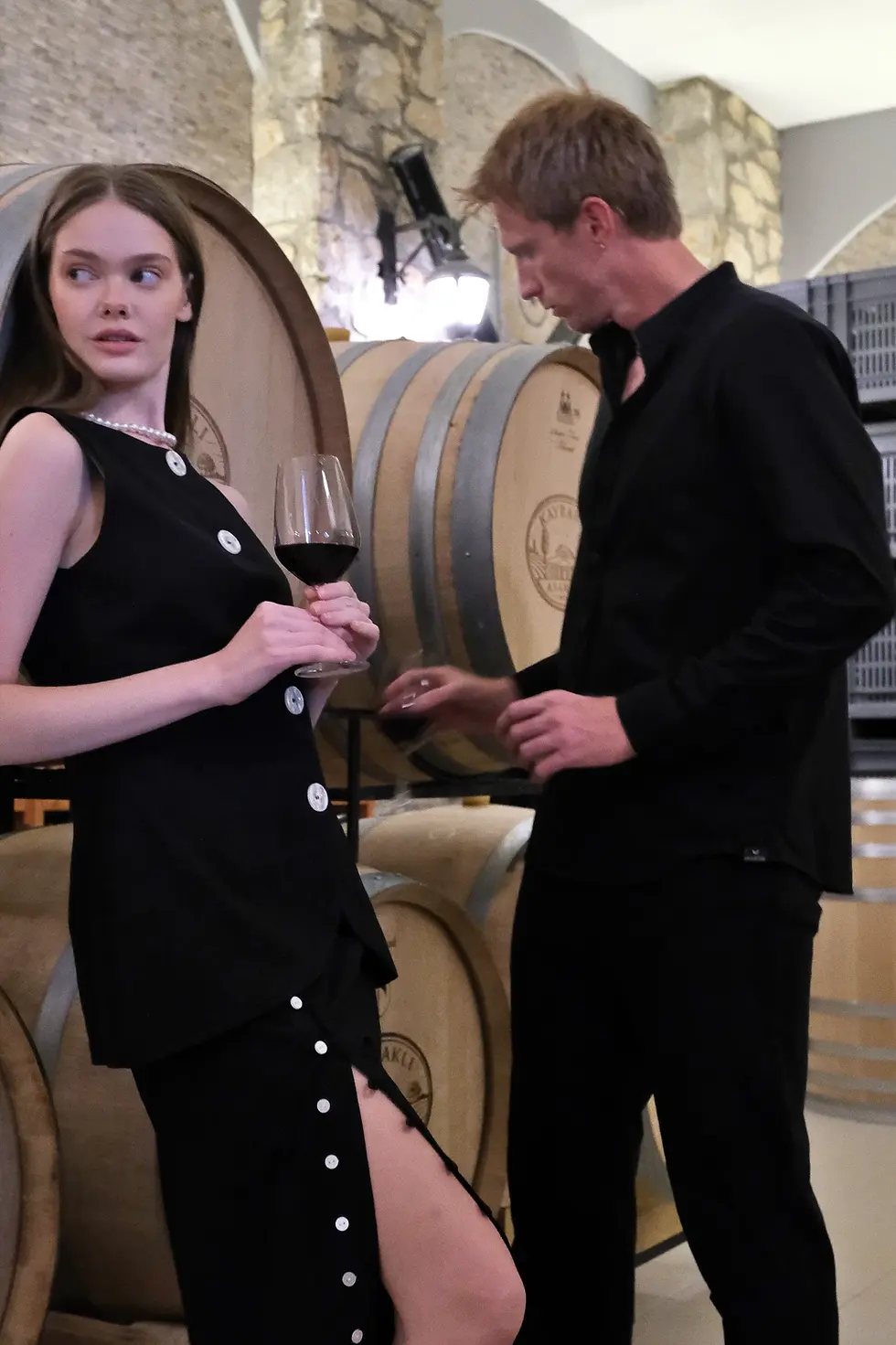 Küçük resim: womens black button loop midi skirt side view with navy blue crop top and mens black outfits on asarcik vineyards scene