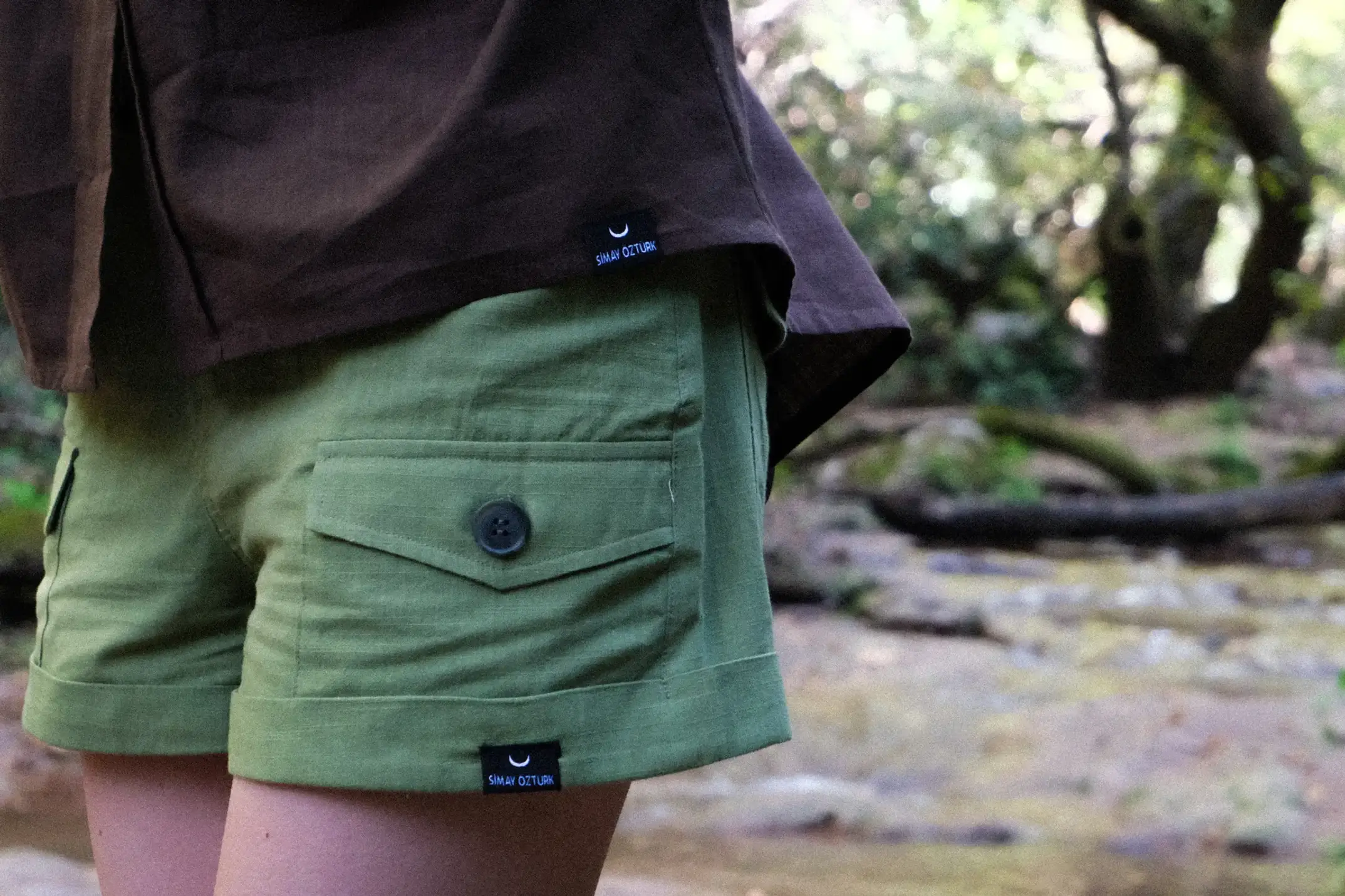womens green cotton shorts with me like summer label and pocket detail close up view with brown shirt