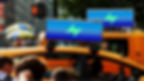 Yellow taxis with blue lightning ads on top in a busy city street. People walking, hot dog stands visible, and a 'stop' crosswalk signal.