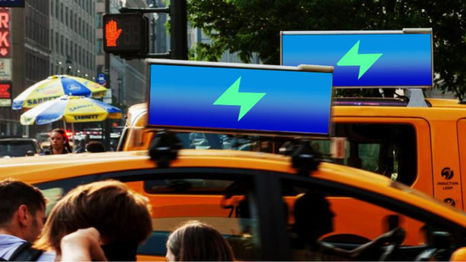 Yellow taxis with blue lightning ads on top in a busy city street. People walking, hot dog stands visible, and a 'stop' crosswalk signal.