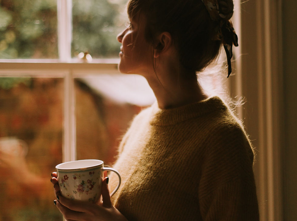 Eine Frau hält nachdenklich eine Kaffeetasse im Büro und unterbricht ihr People Pleasing Muster