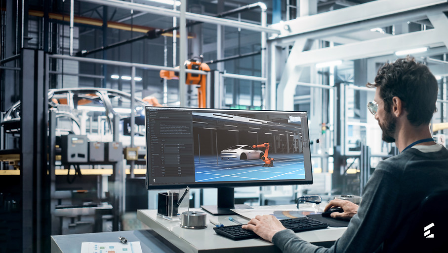A person sitting in front of a computer on a car manufacturing shopfloor simulating the scene using digital twins.