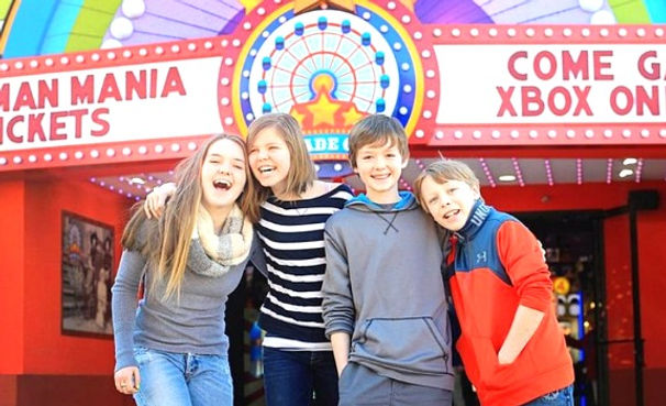 A family stands smiling outside of the Arcade City attraction, in Pigeon Forge Tennessee