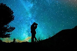 Romantic sillouhette of couple kissing in mountain moonlight under the stars