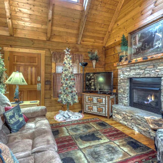 cozy rustic cabin rental with stone fireplace, couch, tv and front door