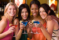 4 happy young women hold their cocktails on a moonshine distillery tour in the Gatlinburg area.
