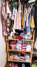 Selection of children's clothing on shelving unit.
