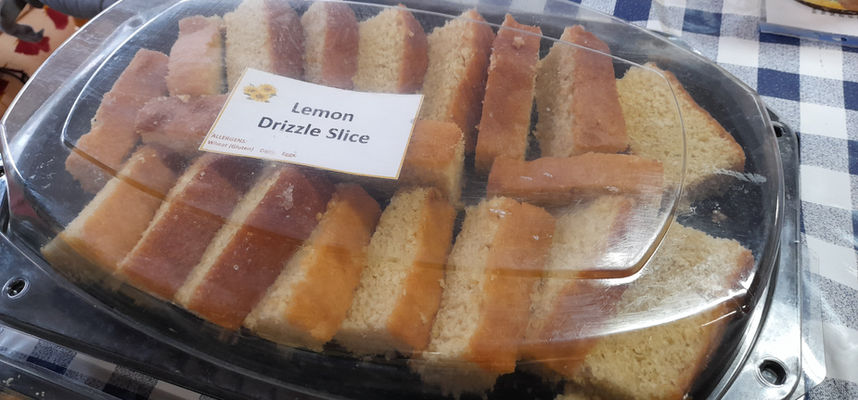 Lemon drizzle cake slices displayed inside a transparent plastic tray