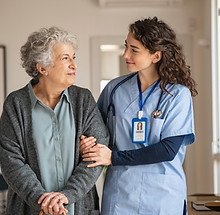 Young caregiver helping senior woman walking Nurse assisting her old woman patient at nurs