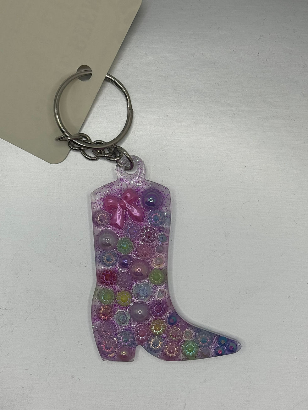Handmade pink and purple glitter resin western cowboy boot key ring with colorful embellishments and pink bow.