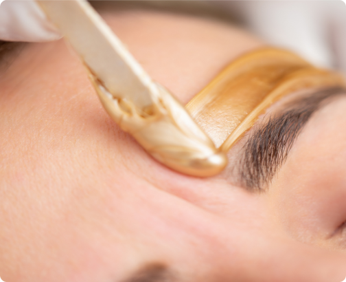 Applying warm gold wax above the eyebrow for shaping