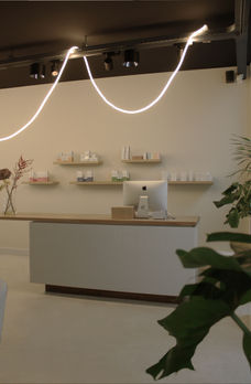 Amsterdam commercial interior design for facial clinic featuring minimalist layout, bespoke mirror wall artwork, and modern treatment spaces in historic city center.